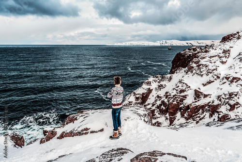 A man standing on a mountain and looking at the sea with dramatic clouds photo