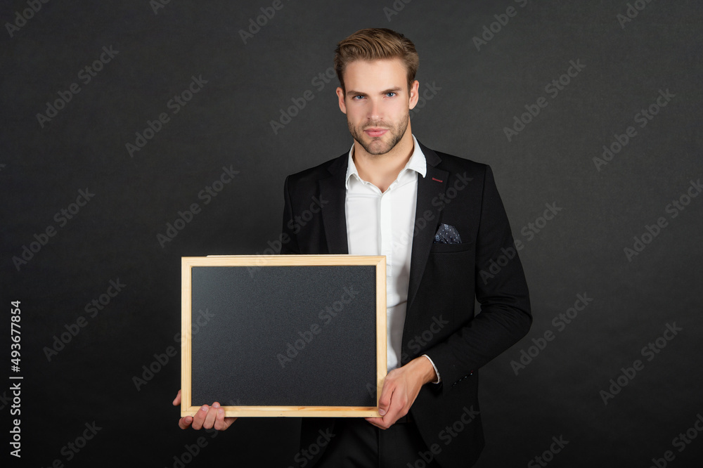Serious guy in formal suit holding empty school blackboard copy space dark background, teacher Serious guy in formal suit holding empty school blackboard copy space dark background, teacher