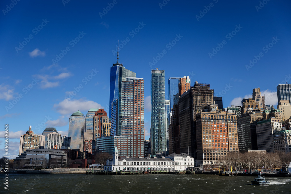 Fototapeta premium Views of Battery Park and the financial district from the water and Ellis Island in New York City