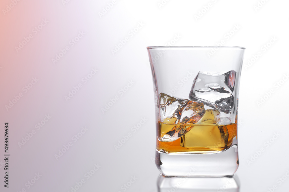 Glass of amber scotch whiskey and ice on a bright background Glass of amber scotch whiskey and ice on a bright background