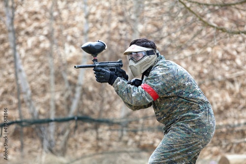 paintball player in a protective clothing aiming his gun at the enemy photo