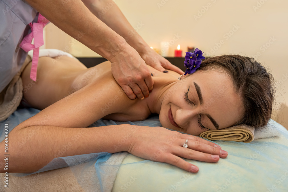 young pretty woman receiving back massage during spa treatment at center. - obrazy, fototapety, plakaty 