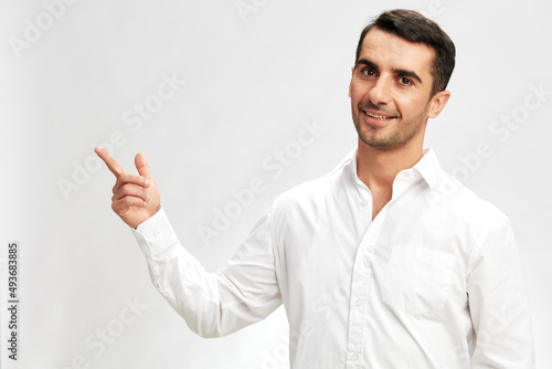 handsome businessman white shirt posing pointing finger to the side light background