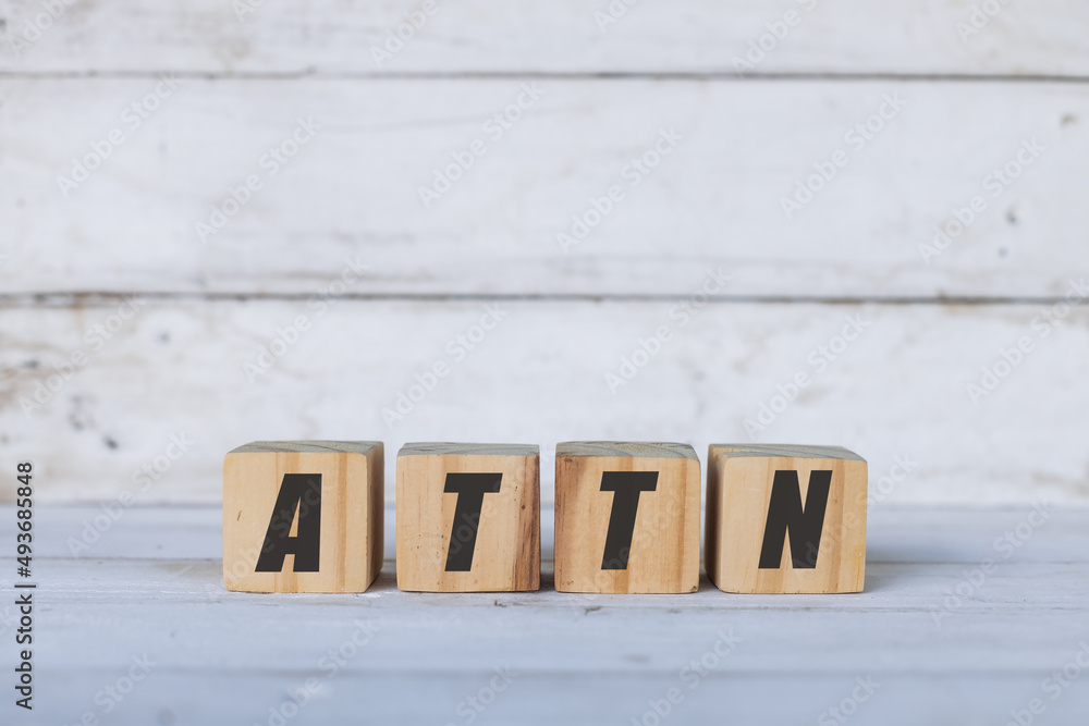 ATTN concept written on wooden cubes or blocks, on white wooden background. ATTN concept written on wooden cubes or blocks, on white wooden background.