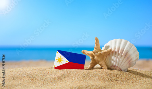 Tropical beach with seashells and Philippine flag. The concept of a paradise vacation on the beaches of the Philippines.