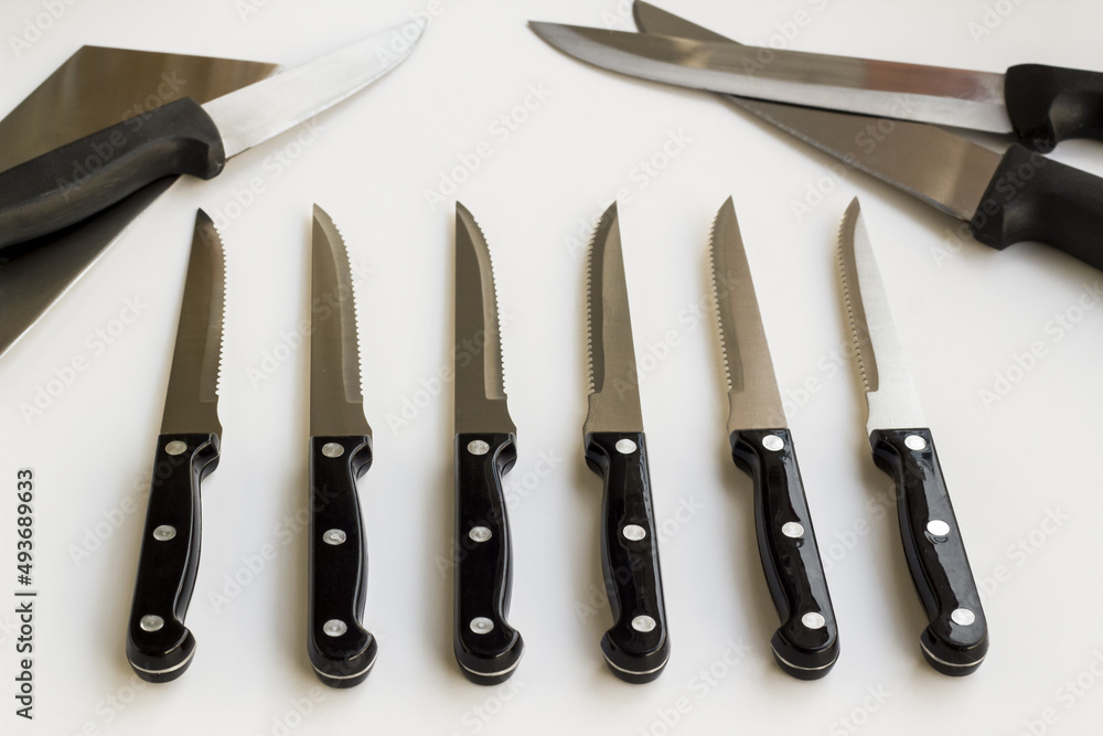 Unused,new knife set of different knives lined up on a white surface Unused,new knife set of different knives lined up on a white surface