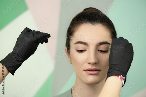 Eyebrow correction procedure. Brow shaping by thread depilation technique photo