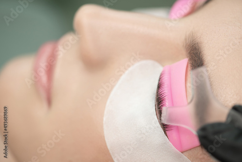 Master glues eyelashes to lash roller by applicator. Close-up of beauty model's face during lash lift laminating botox procedure. Eyelash Care Treatment: eyelash lifting and curling, lash lamination  photo
