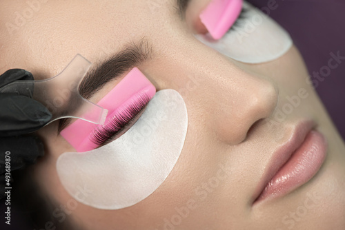 Master glues eyelashes to lash roller by applicator. Close-up of beauty model's face during lash lift laminating botox procedure. Eyelash Care Treatment: eyelash lifting and curling, lash lamination