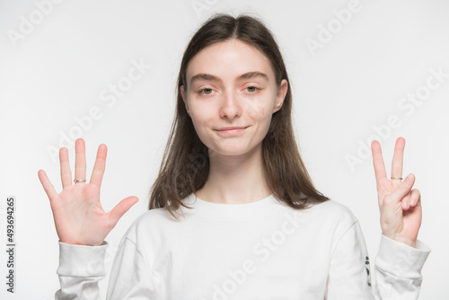 Wallpaper Mural close-up portrait of a young Ukrainian girl who shows the number with her hands on a white background
 Torontodigital.ca