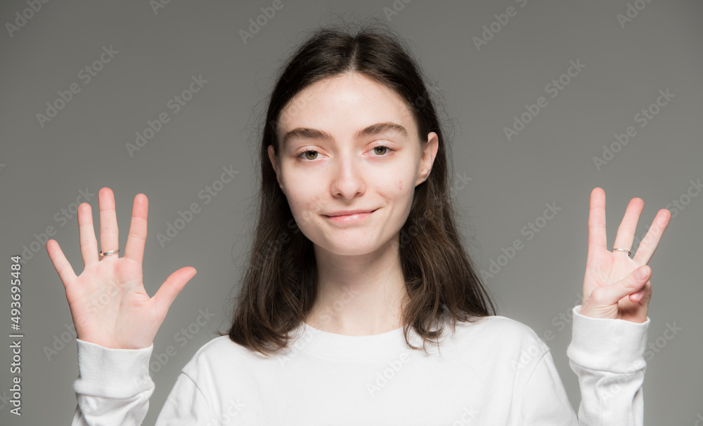 close-up portrait of a young Ukrainian girl who shows the number with her hands on a gray background close-up portrait of a young Ukrainian girl who shows the number with her hands on a gray background