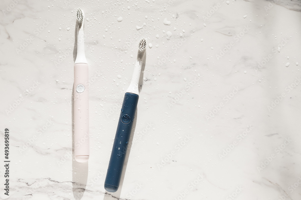 New modern ultrasonic toothbrush with splashes and drops of water on marble background. Oral hygiene, dental and gum health, healthy teeth. Dental products Ultrasonic vibration toothbrush. New modern ultrasonic toothbrush with splashes and drops of water on marble background. Oral hygiene, dental and gum health, healthy teeth. Dental products Ultrasonic vibration toothbrush.
