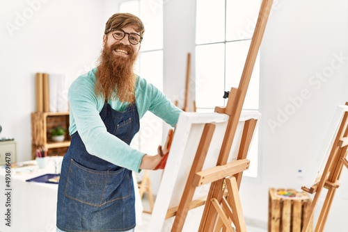 Young redhead man smiling confident painting with palm hands at art studio