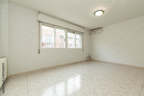 Empty living room with light glossy stoneware flooring  large aluminum window and air conditioner