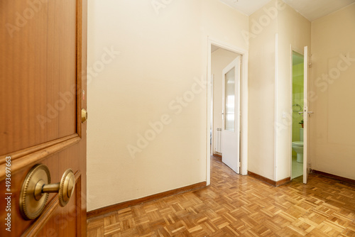 Entrance door and distributor hall of a residential house with entrance to a furnished living room, toilet and oak parquet floors