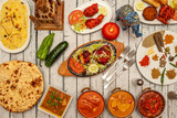 Typical Indian food dishes with many curries, mild and strong, naan, pilau rice, tandoori chicken, peppers and cucumbers and various spices