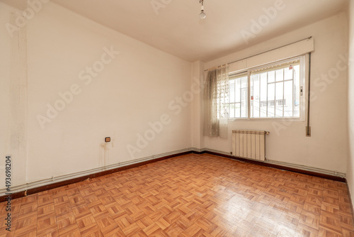 empty room with similar wood sintasol floors  aluminum window with bars and white aluminum radiators