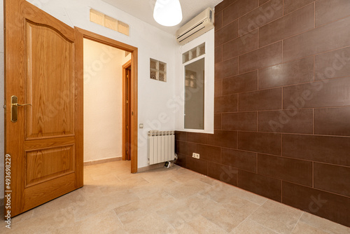 Wallpaper Mural Empty room with a wall covered in dark brown tiles, a window and a pine wood door Torontodigital.ca