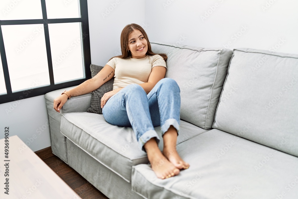 Young hispanic woman smiling confident sitting on the sofa at home