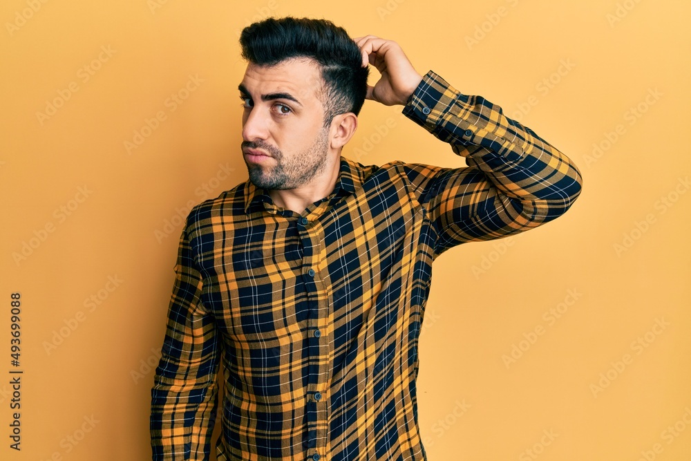 Young hispanic man wearing casual clothes confuse and wondering about question. uncertain with doubt, thinking with hand on head. pensive concept. Young hispanic man wearing casual clothes confuse and wondering about question. uncertain with doubt, thinking with hand on head. pensive concept.