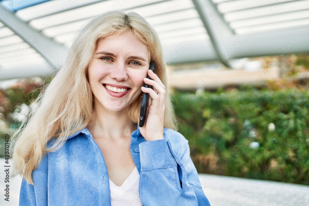Young blonde woman outdoors on a sunny day speaking on the phone Young blonde woman outdoors on a sunny day speaking on the phone
