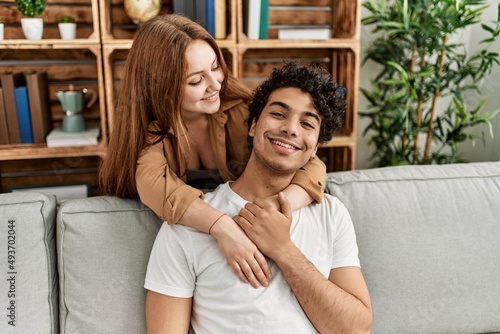 Young couple smiling happy and hugging sitting on the sofa at home.
