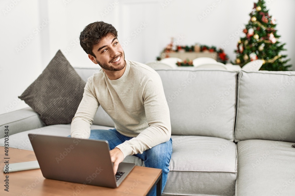 Young hispanic man smiling happy sitting on the sofa using laptop at home. Young hispanic man smiling happy sitting on the sofa using laptop at home.