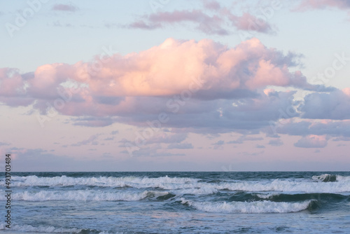 Pastel color sunset clouds and crashing waves