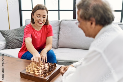 Middle age man and woman couple smiling confident playing chess at home