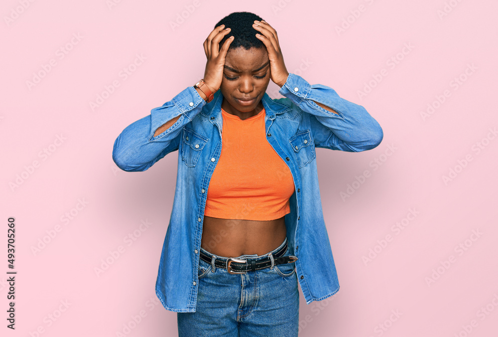 Young african american woman wearing casual clothes suffering from headache desperate and stressed because pain and migraine. hands on head. Young african american woman wearing casual clothes suffering from headache desperate and stressed because pain and migraine. hands on head.