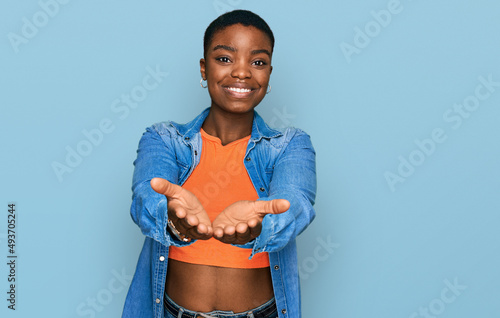 Fotótapéta Young african american woman wearing casual clothes smiling with hands palms together receiving or giving gesture