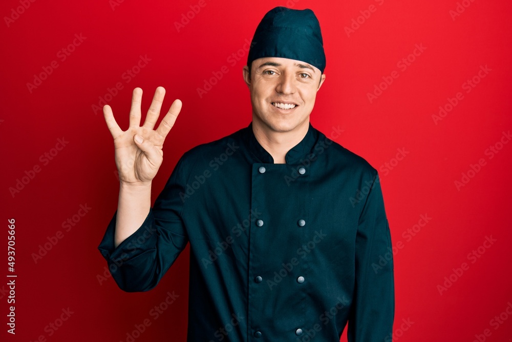 Handsome young man wearing professional cook uniform and hat showing and pointing up with fingers number four while smiling confident and happy. Handsome young man wearing professional cook uniform and hat showing and pointing up with fingers number four while smiling confident and happy.