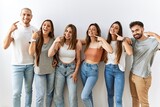 Group of young friends standing together over isolated background smiling cheerful showing and pointing with fingers teeth and mouth. dental health concept.