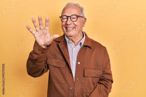 Senior man with grey hair wearing casual jacket and glasses showing and pointing up with fingers number five while smiling confident and happy.