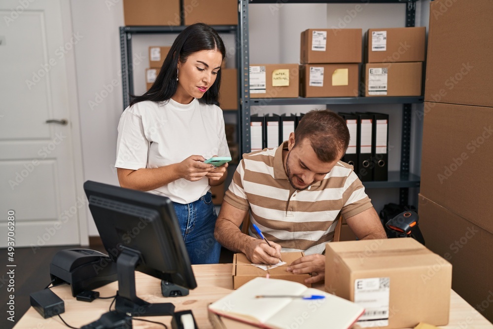 Man and woman business workers using smartphone working at storehouse Man and woman business workers using smartphone working at storehouse