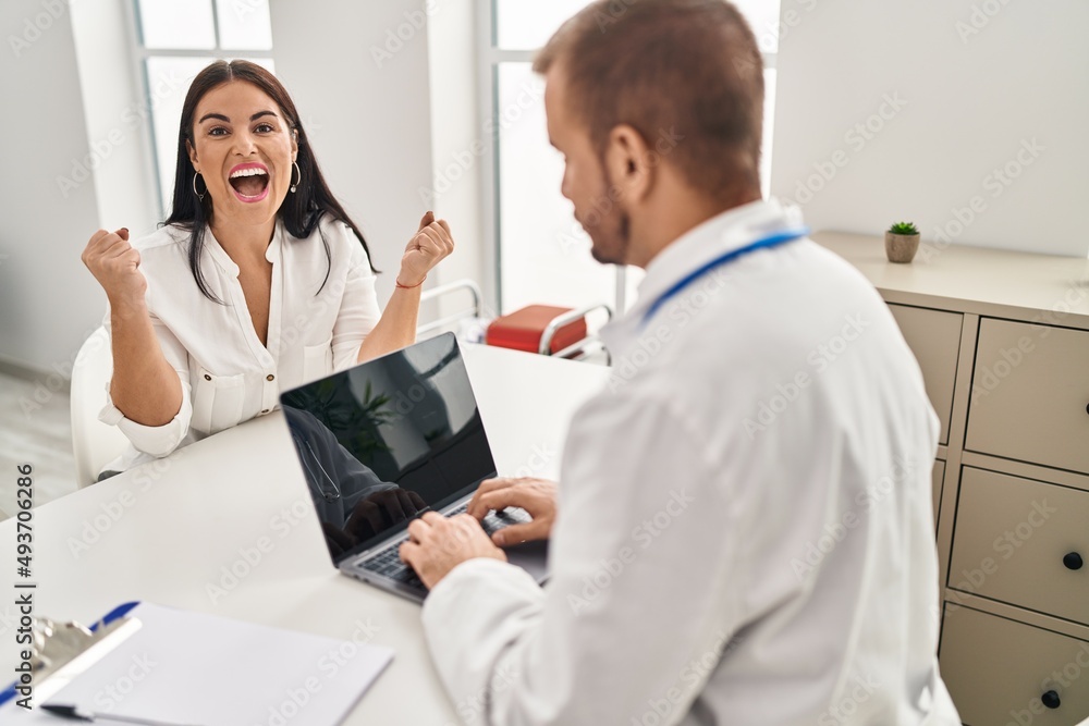 Young hispanic woman at the doctor screaming proud, celebrating victory and success very excited with raised arms Young hispanic woman at the doctor screaming proud, celebrating victory and success very excited with raised arms