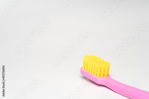 toothbrush with pink handle yellow brush head. Toothbrush closeup on white background.