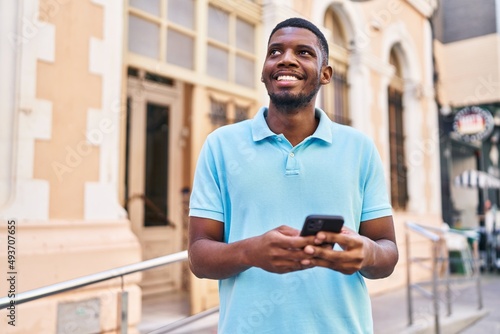 Young african american man smiling confident using smartphone at street