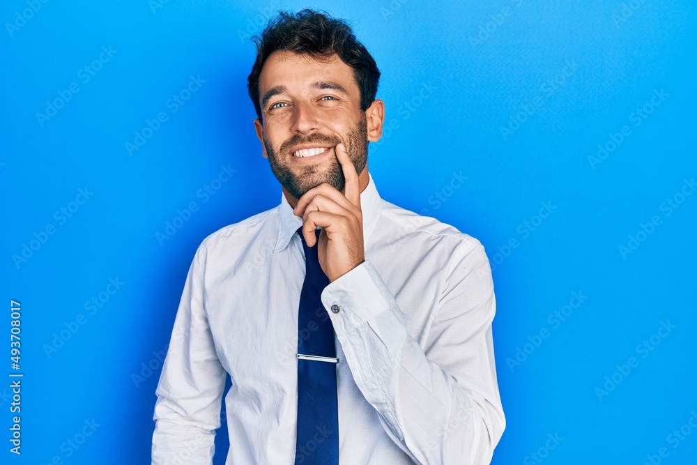 Handsome man with beard wearing business shirt and tie smiling looking confident at the camera with crossed arms and hand on chin. thinking positive. Handsome man with beard wearing business shirt and tie smiling looking confident at the camera with crossed arms and hand on chin. thinking positive.