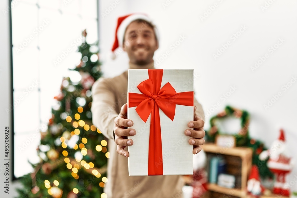Young hispanic man smiling confident holding christmas gift at home Young hispanic man smiling confident holding christmas gift at home