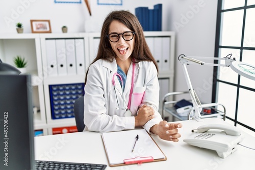 Young doctor woman wearing doctor uniform and stethoscope at the clinic winking looking at the camera with sexy expression  cheerful and happy face.