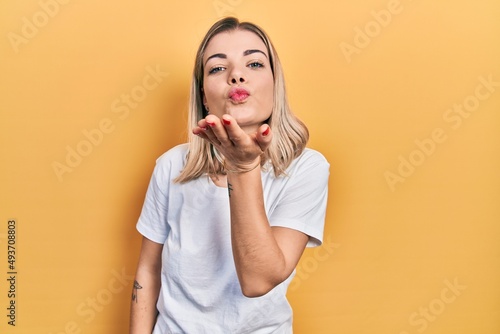 Beautiful caucasian woman wearing casual white t shirt looking at the camera blowing a kiss with hand on air being lovely and sexy. love expression.