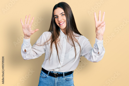 Young brunette teenager wearing business white shirt showing and pointing up with fingers number eight while smiling confident and happy.