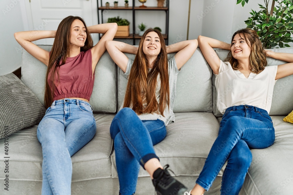 Three young hispanic woman smiling happy relaxed with hands on head sitting on the sofa at home. Three young hispanic woman smiling happy relaxed with hands on head sitting on the sofa at home.
