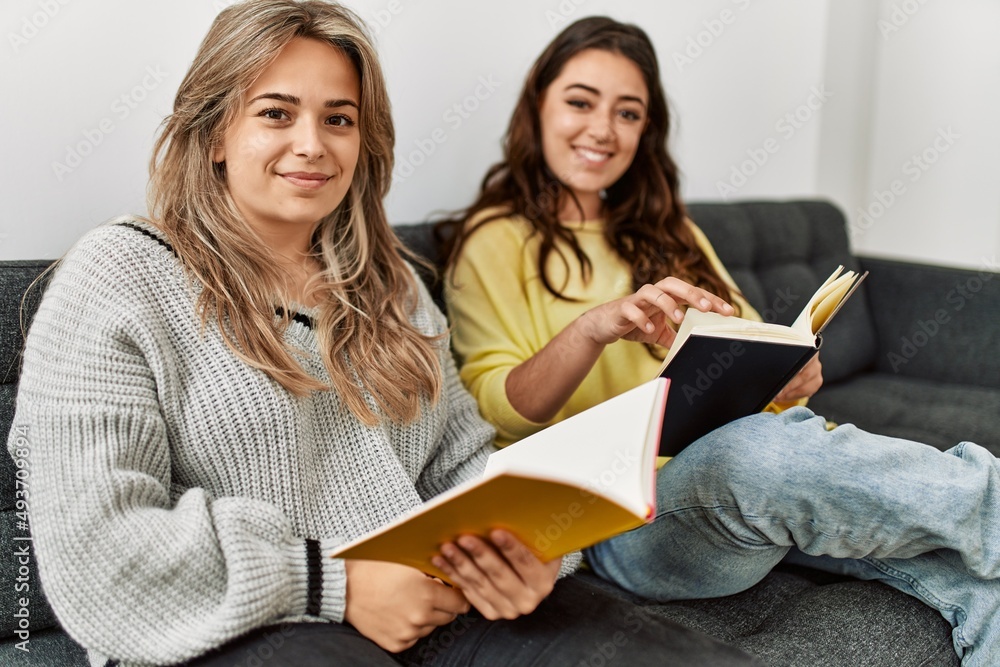 Young couple reading book sitting on the sofa at home. Young couple reading book sitting on the sofa at home.