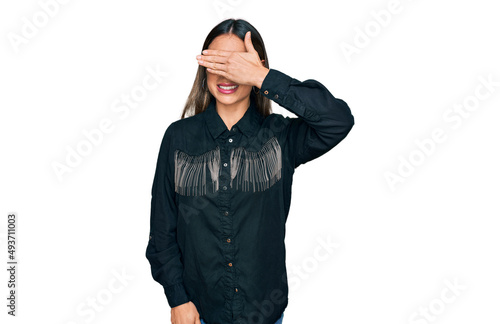 Young hispanic woman wearing casual clothes smiling and laughing with hand on face covering eyes for surprise. blind concept.