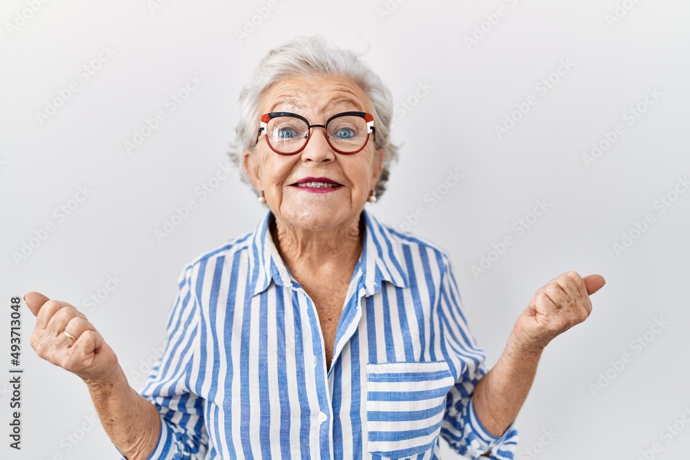 Senior woman with grey hair standing over white background celebrating surprised and amazed for success with arms raised and open eyes. winner concept. Senior woman with grey hair standing over white background celebrating surprised and amazed for success with arms raised and open eyes. winner concept.