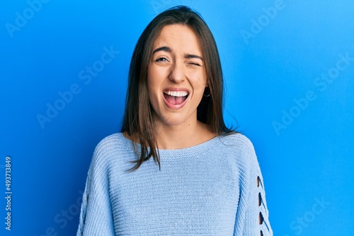 Young hispanic girl wearing casual clothes winking looking at the camera with sexy expression, cheerful and happy face.
