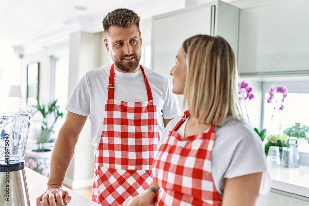 Obraz premium Young couple smiling confident cooking at kitchen