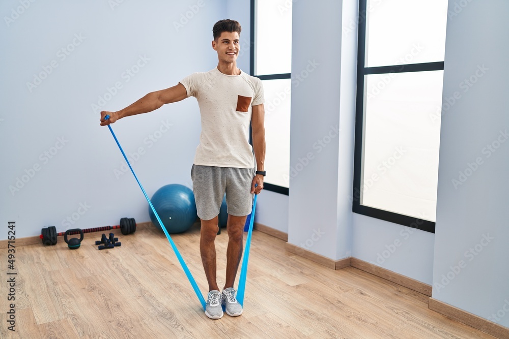 Young hispanic man smiling confident training using elastic band at sport center Young hispanic man smiling confident training using elastic band at sport center